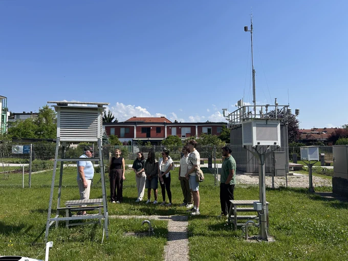 Water-R20 NRT students attend an outdoor presentation at a meteorological monitoring station in Slovenia, with measurement equipment visible in the background.