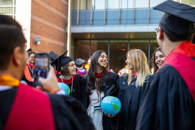 Graduates smiling and laughing at one another.
