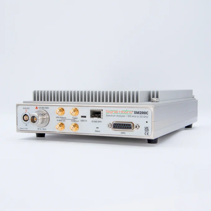 A Signal Hound SM200C spectrum analyzer is shown. It features several ports including USB, Ethernet, and multiple RF connectors. The device is set against a plain light background.