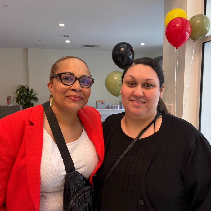Angie Boddie (left), NCBA Director of Health Programs, and ACL's Nicole Becerra pose smiling for the camera in front of multicolored balloons at the health fair