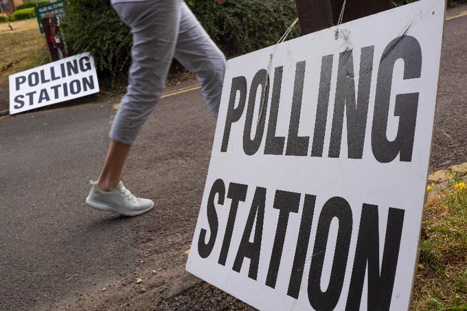 Polling Station sign and a person walking past