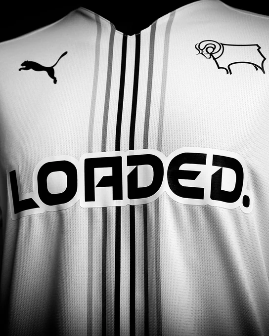 An image of the front of Derby County's new white 2026/27 PUMA home shirt - with six greyscale pinstripes down the centre, and the Loaded sponsor logo across the front. The shirt also includes a black V-neck collar and PUMA and Derby County logos. 