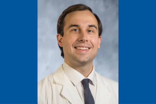Headshot of Eugene Vaios, MD, MBA, on blue background