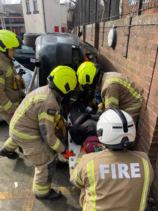 Four firefighters around a dummy performing a rescue at a road traffic collision training exercise.