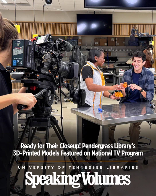 People film a demonstration in a lab while two individuals hold orange 3D-printed models. Text reads Ready for Their Closeup! Pendergrass Library’s 3D-Printed Models Featured on National TV Program.