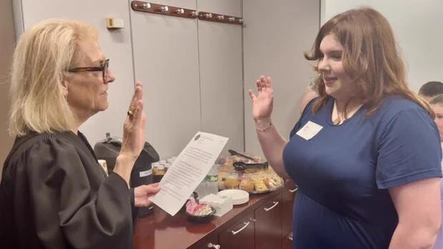 Trial Court Chief Justice Heidi E. Brieger administers a ceremonial oath to a student participant during the Massachusetts Probation Service “Co-Commissioner for the Day” program as both raise their right hands in an office setting.