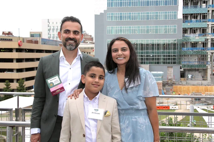 family posing and smiling on a balcony overlooking UAB campus