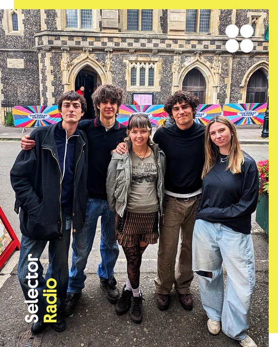 Four band members (MORN) pose with Selector host Sian Eleri together on a Brighton street in front of a historic stone church building (FABRICA). The Selector Radio logo is in the bottom left corner, while the British Council logo (four circles) is in the top right. The border is yellow. 