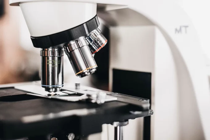 Close-up of a laboratory microscope focusing on the objective lenses and stage with a slide in place.