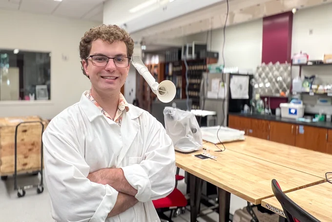 Colton Byrne wearing a white lab coat standing in Dr. Totten's lab at The University of Alabama.