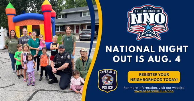 Group of children, adults, and a police officer posing in front of a colorful bounce house during one of Naperville's National Night Out events in 2025.
