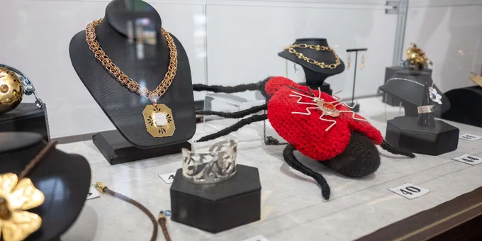 Display of intricate gold and silver jewelry including necklaces and rings in a glass case with numbered tags.