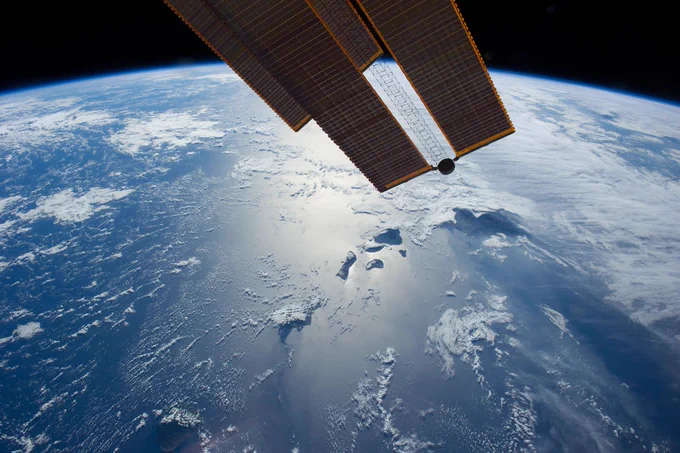 (28 July 2014) --- Flying 225 nautical miles above the Hawaiian Ridge in the North Pacific Ocean, one of the Expedition 40 crew members on the International Space Station photographed this oblique panorama showing many of the islands in the Hawaiian chain, some of them highlighted by sun glint. Hawaii or the "Big Island" is largely covered by clouds at right center. Maui, Kahoolawe, Lanai and Molokai are more easily spotted because of the sun glint near frame center. Oahu is almost totally hidden by clouds at bottom center, and Niihau and Kauai are out of the frame. Part of one of the orbital outpost's solar panels is obvious at top center.