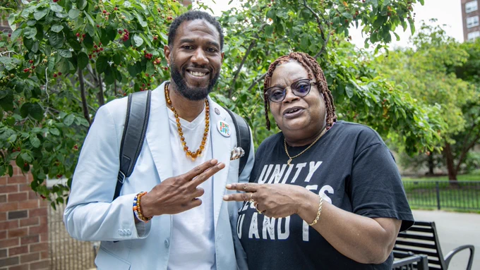 The Public Advocate smiles and poses with the Grand Street Guild Residents Association president, Sandra Strother. Both hold peace signs