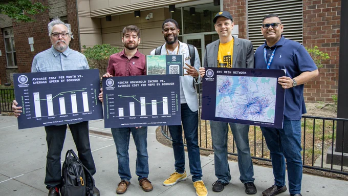 The Public Advocate holds up a QR code for the report, as staff members and tech equity advocates from NYC Mesh and Community Tech NY hold charts and smile