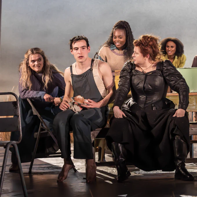 Eanna Harwicke and Siobhan McSweeney sit at a table surrounded by girls who are very interested.