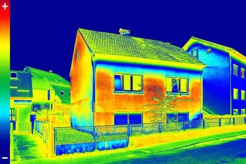 Thermal image of houses showing heat distribution. Warmer areas in red and orange, cooler areas in blue. Scale indicates temperature range.