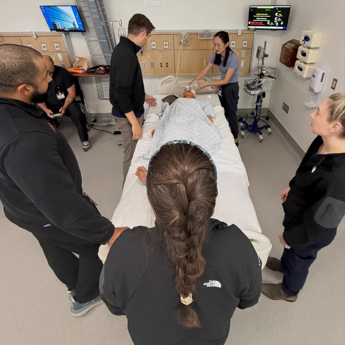 View from the foot of the simulated patient's bed while residents review polytrauma airway techniques with a simulation faculty member. 