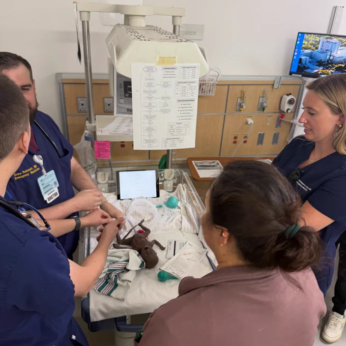 Simulation fellow and three emergency medicine residents gather around an isolette to discuss our neonatal resuscitation program.