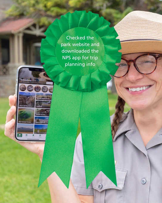 A large green ribbon atop a photo of a park ranger smiling and holding up a cell phone with the NPS app open on it. Text on the ribbon reads: "Checked the park website and downloaded the NPS app for trip-planning info."