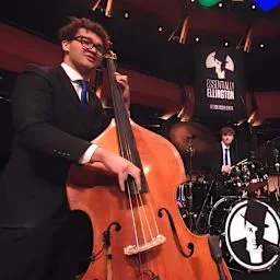 A young man plays jazz on the standing bass.