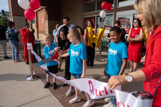 Students use giant scissors to cut the ribbon at Burlington Stores.