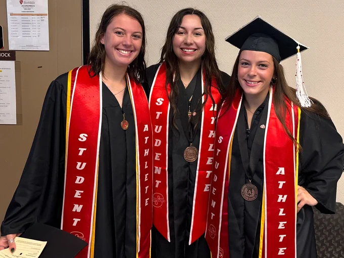 Three Stan State Soccer players posing indoors for commencment.