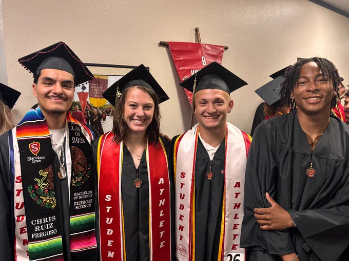 Four Stan State Track members posing indoors before commencement.