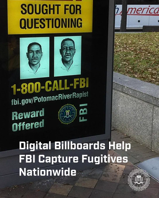 FBI digital billboard displaying two wanted individuals with a reward offered and contact information for tips.