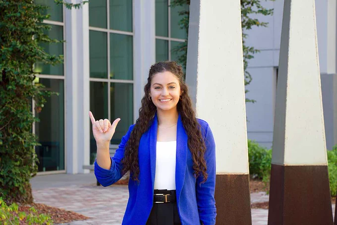 a photo of a student smiling outside of lutgert hall