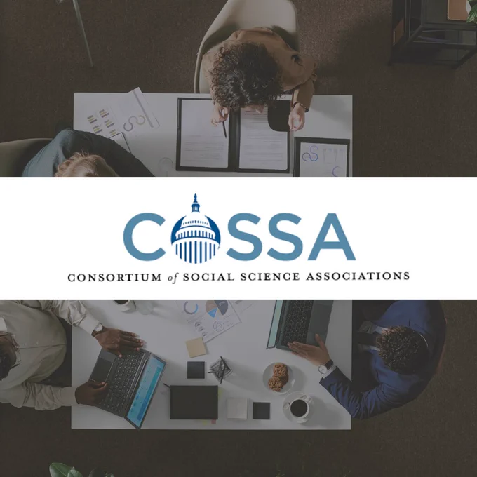 Overhead view of a diverse team collaborating on documents and laptops around a white table in an office setting.