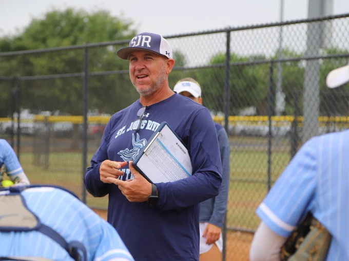 Coach holding a clipboard and talking to the team before a game.