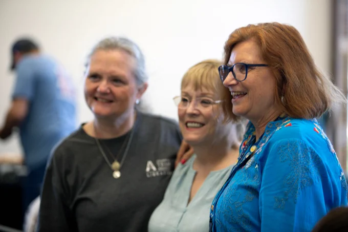 Pictured is a photo of UTA Libraries staff member Bonnie Dreitner posing for a photo with two other people.