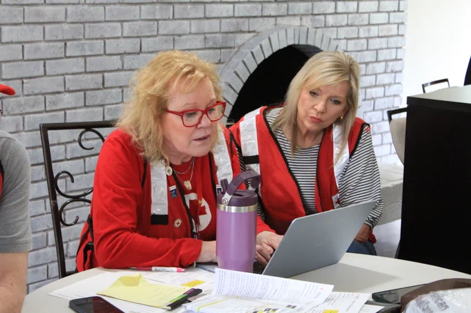 Two Red Cross volunteers filling out forms on a laptop