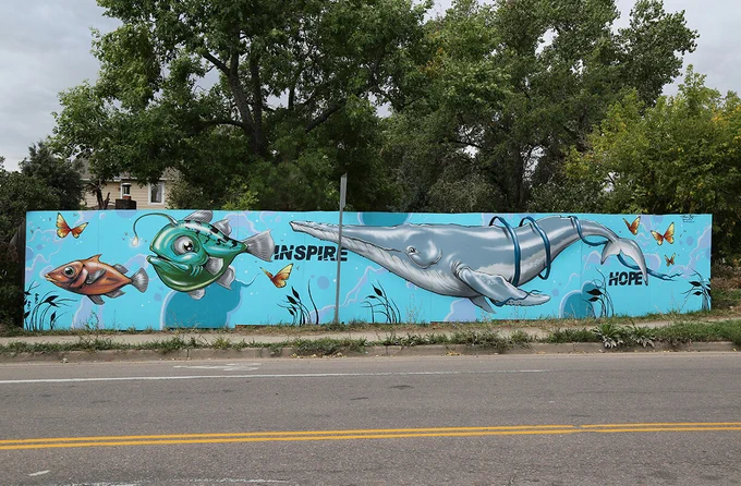 Mural on neighborhood fence with sea creatures and the words 'inspire' and 'hope'