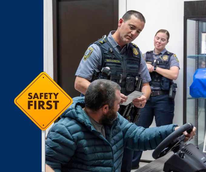 Police officers checking identification of a man seated in a vehicle inside a building, emphasizing safety protocols.
