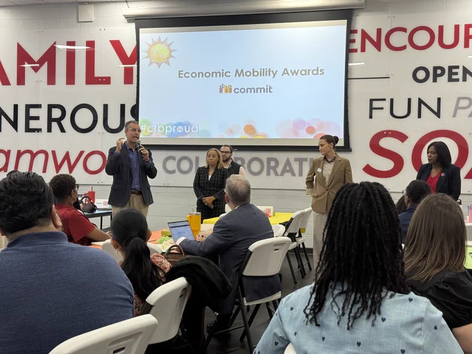 A group of people seated in a conference room, with a presentation screen displaying the "Economic Mobility Awards" logo.