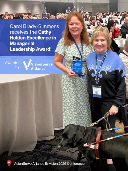 A photo of Carol Brady-Simmons and Virginia Jacko with her Guide Dog Sama, smiling for the camera at the VisionServe Alliance Envision 2026 Conference. Overlayed, is text: Carol Brady-Simmons receives the Cathy Holden Excellence in Managerial Leadership Award! Awarded by: VisionServe Alliance"