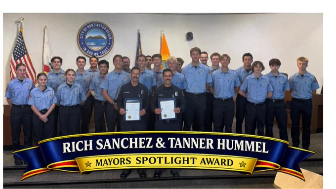 Group photo of Huntington Beach Fire Explorers standing with Firefighter/Paramedics Rich Sanchez and Tanner Hummer during a Mayor’s Spotlight Award recognition ceremony at Huntington Beach City Hall. Sanchez and Hummer hold award certificates while surrounded by Fire Explorers in uniform. A blue and gold banner at the bottom recognizes them as HBFD Fire Explorer Advisors.