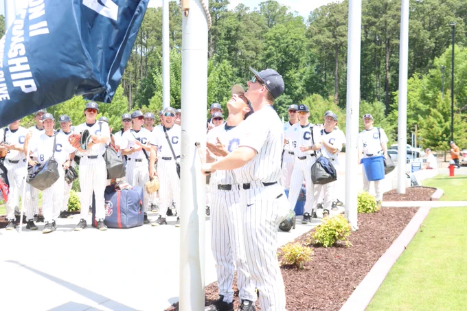 Casey Gouge and Ty Hubbard raise the Catawba flag at the USA Baseball Training Complex.