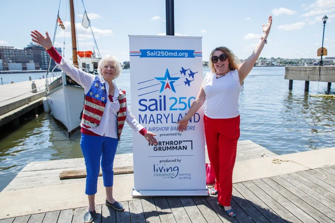 Photo of County Executive Klausmeier and Dorothy Yeager standing in front of a Sail250 sign on the water in Fells Point, Baltimore.