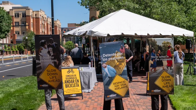 As the press event goes on, campaign members wear large pedestrian and bicycle safety signs that read “Slow Down Life Ahead” in English and Spanish.