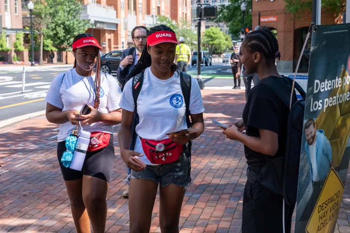 A Street Smart campaign member shares information with two pedestrians passing by Holland Lane. 