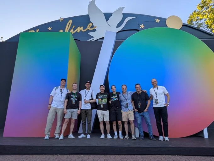 A group of people in front of a large prop of the I/O logo.