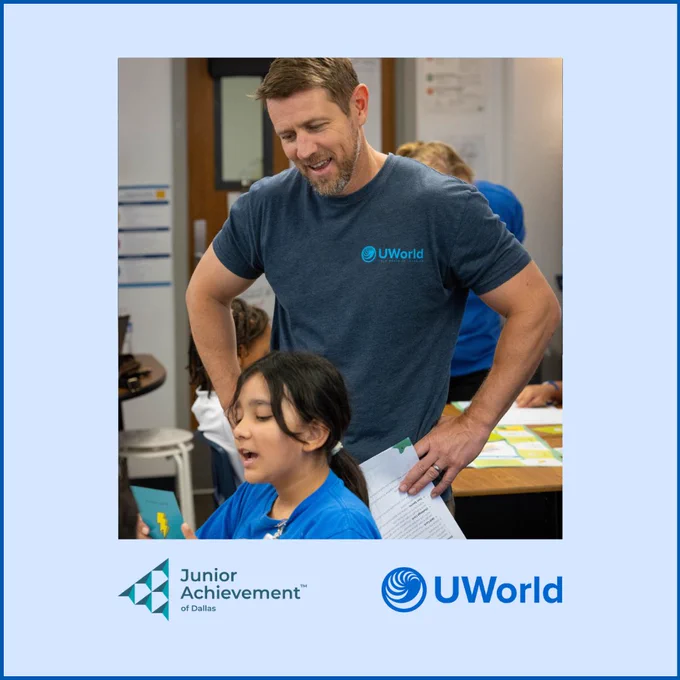 A person in a UWorld t-shirt is engaging with a young student in a classroom setting. The image features logos for Junior Achievement of Dallas and UWorld.