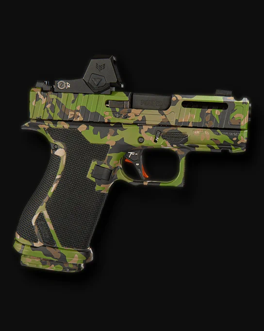 Custom multicam camouflage pistol with optic, compensator-style slide cuts, extended magazine base plate, and black textured grip shown against a black background.