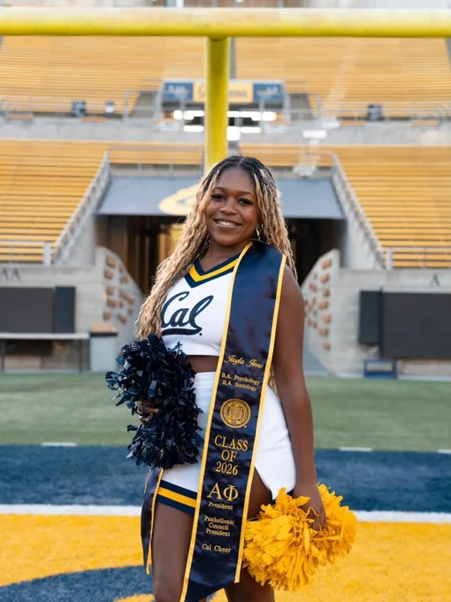 A UC Berkeley graduate poses in their cheerleader attire and graduation stole inside Memorial Stadium. @jaylajerro on Instagram