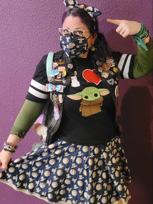 Ruth, wearing a Grogu-themed ensemble, including a Grogu-themed headband, cover for her glasses, KN95 respirator, skirt, T-shirt and socks, posed for a selfie at a movie hall in CA to raise awareness about prevention with MaskTogetherAmerica.