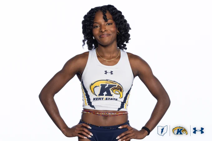 An athlete poses confidently wearing a Kent State athletic uniform. The uniform prominently features the Kent State logo on a sleeveless top. Under Armour logos are also visible on the uniform. Three logos are displayed at the bottom right: one resembling a map, one with "K" and a bird, and an Under Armour logo.
