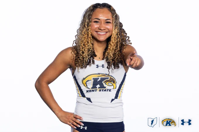 An athlete in a Kent State uniform is smiling and pointing towards the camera. Several logos are visible in the bottom corners, including the Kent State logo and the Under Armour logo.